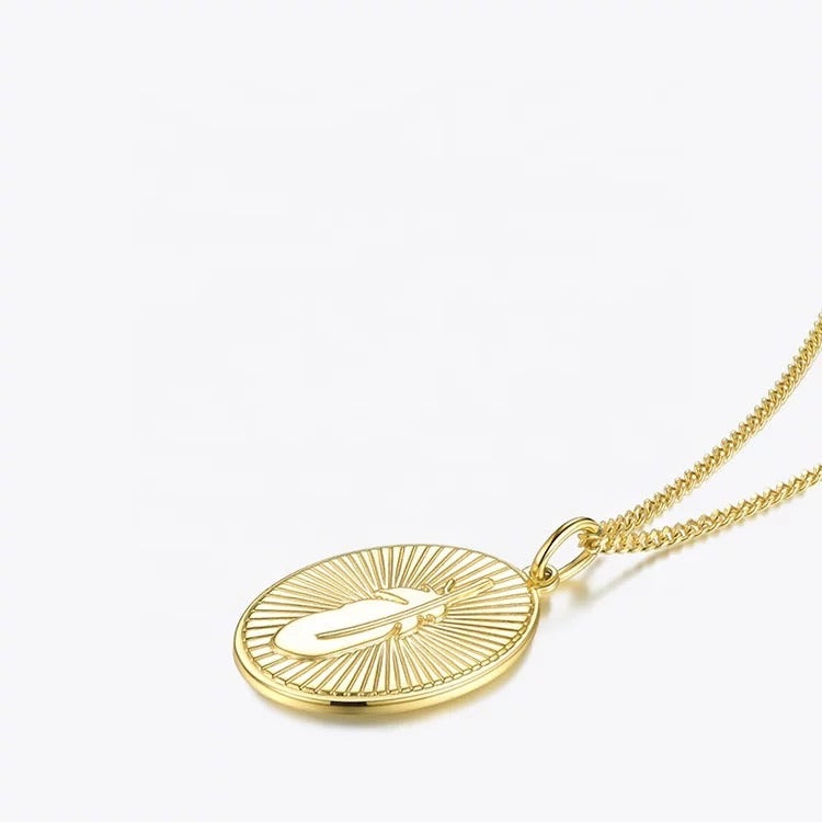 Close-up of gold necklace with feather pendant and chain